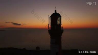 工作的老灯塔上一个日落背景在海上在夏天空中飞行的无人机经过灯塔